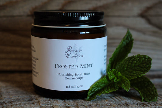 Jar of Frosted Mint body butter with a sprig of mint on a wooden surface